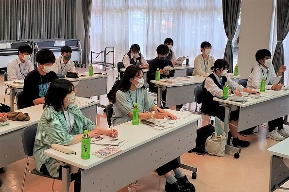 長机が設置された室内で、2名ずつ着席したメンバーが小川町について真剣に学んでいる会議の様子の写真