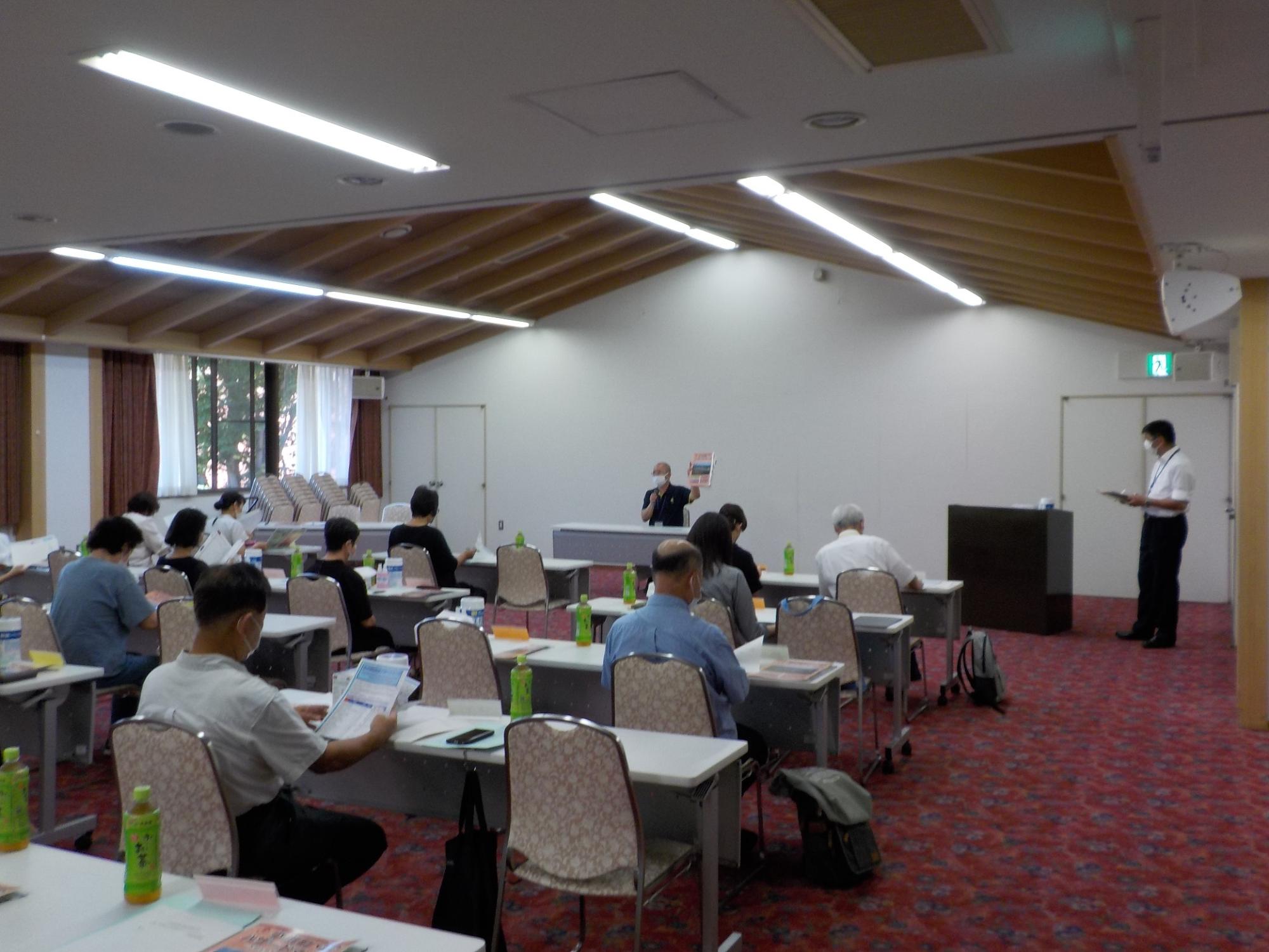 参加者たちが会議室の長机の前にある椅子に座り、防災研修を受けている写真