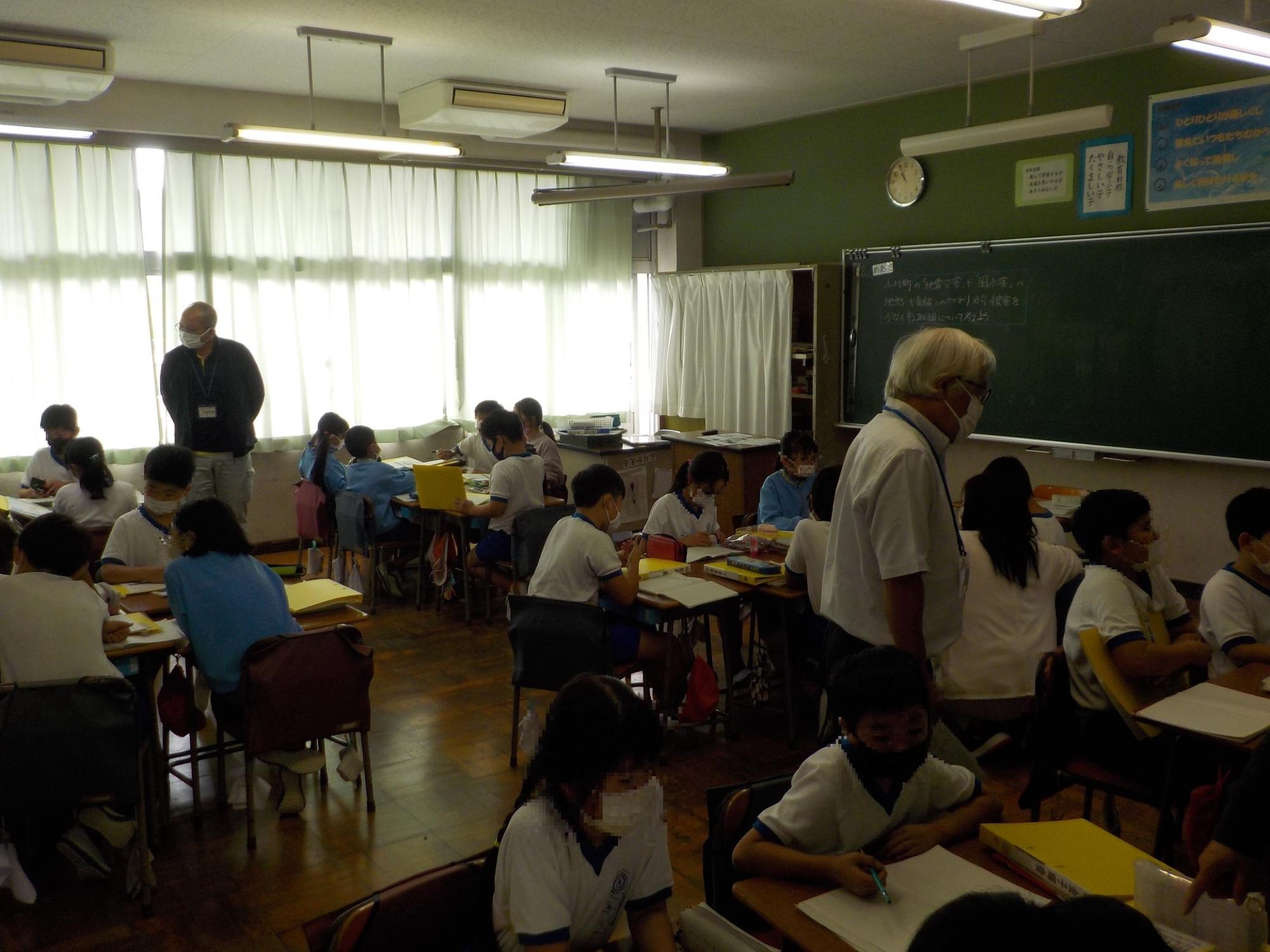 教室で小学生たちがいくつかのグループに分かれて防災授業を受けている写真