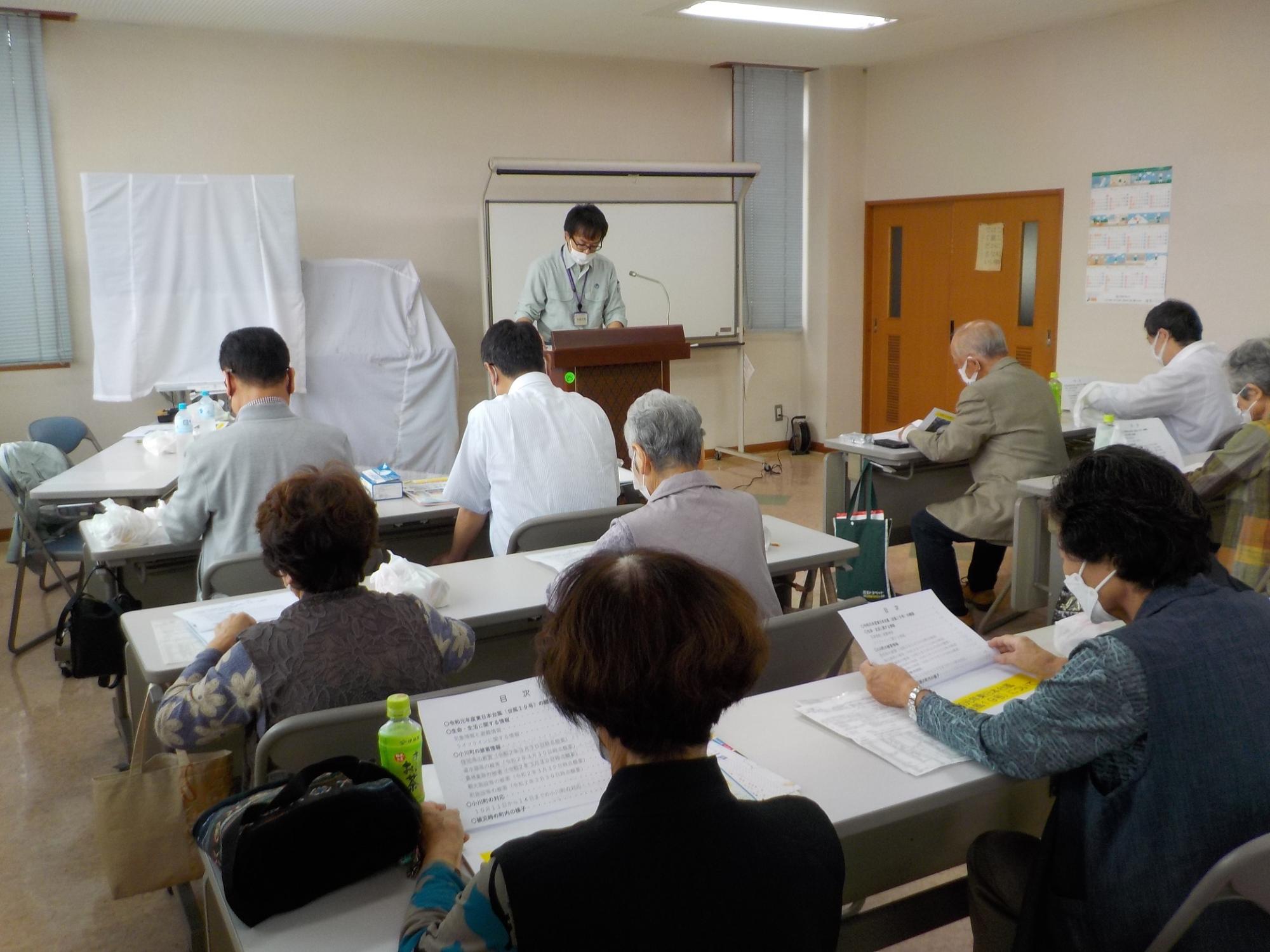 部屋の中で男性講師の話を聞く参加者たちの写真