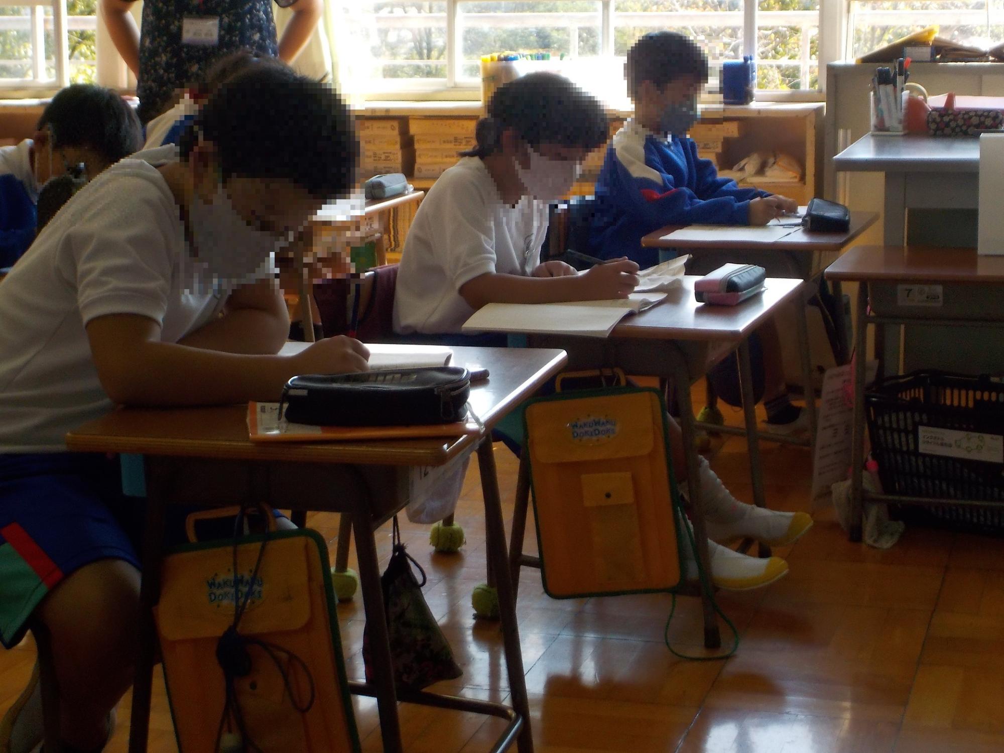 教室で小学生たちが机の前の椅子に座って防災授業を受けている写真