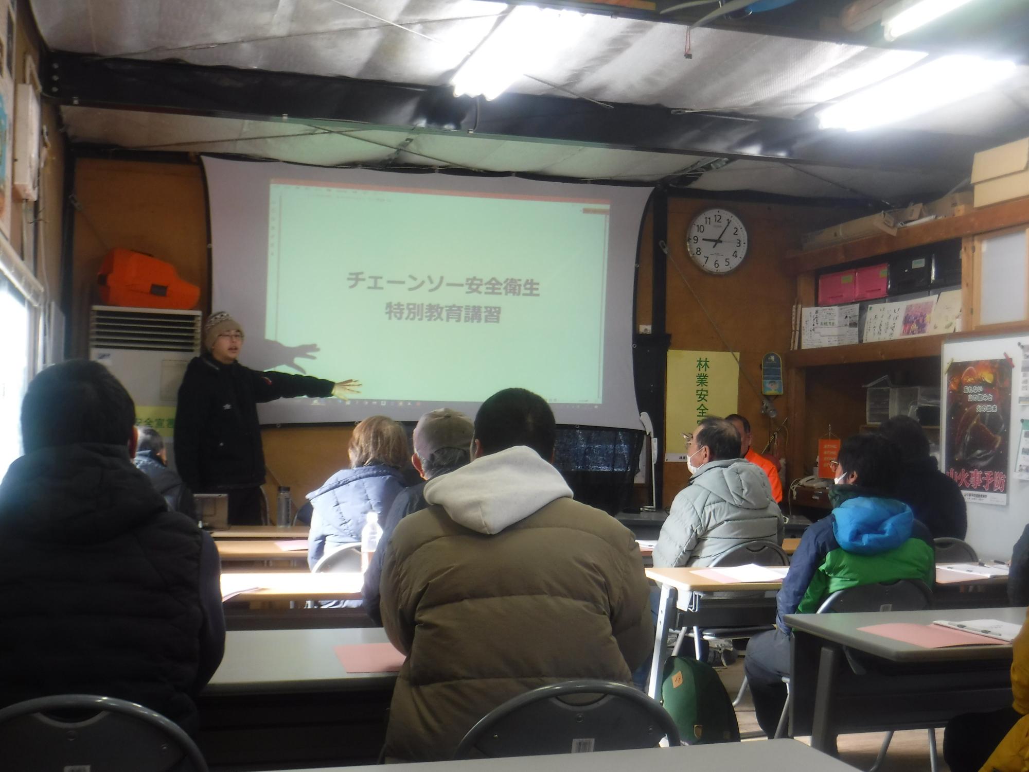 部屋の中でチェーンソーの講習を受けている人々の写真