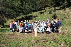 植樹会に参加されたたくさんの人たちが記念柱の後ろに並んで記念撮影をしている写真