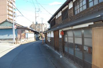 細い道の側面に建つ格子状のガラスの扉や窓がある古い建物の外観を撮影した写真