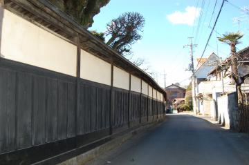 細い道沿いに続く白い壁と黒塀を通路側から撮影した写真