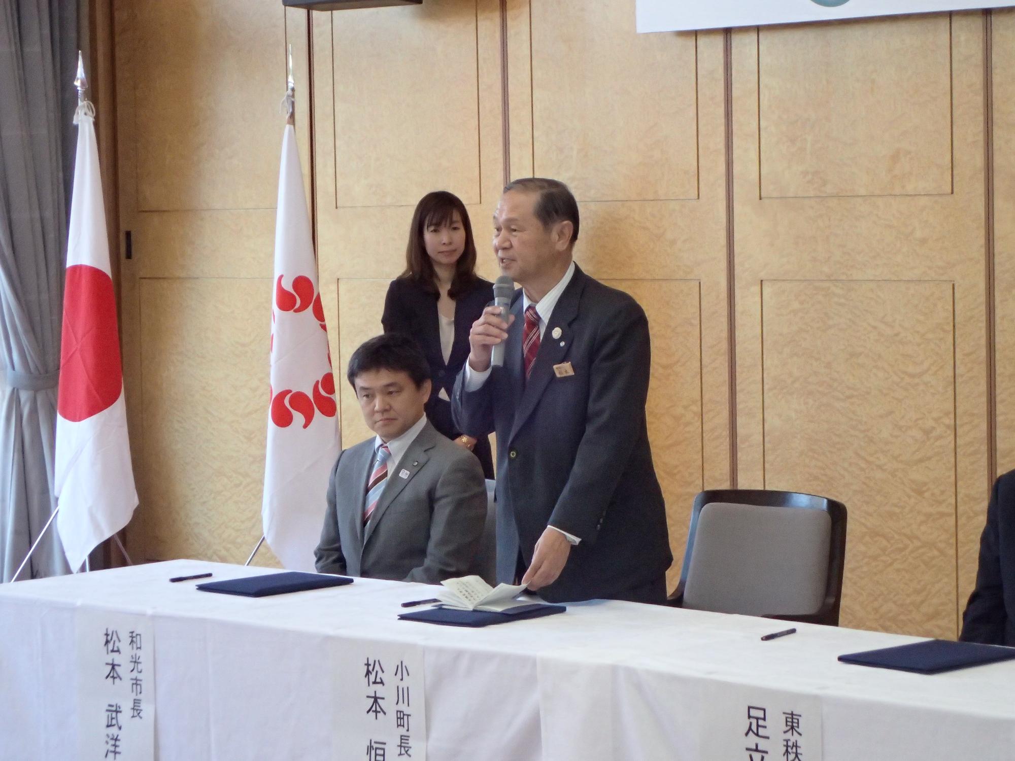 和光市長の横でマイクを持って立ち話をしている小川町長の様子をななめ前から撮影した写真