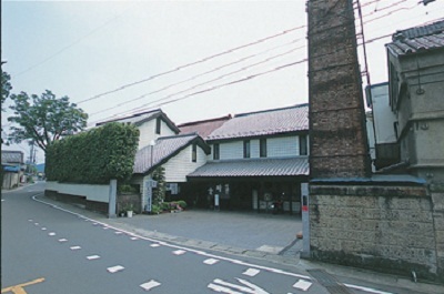道路沿いに建つ赤茶色い屋根づくりの晴雲酒造の外観写真
