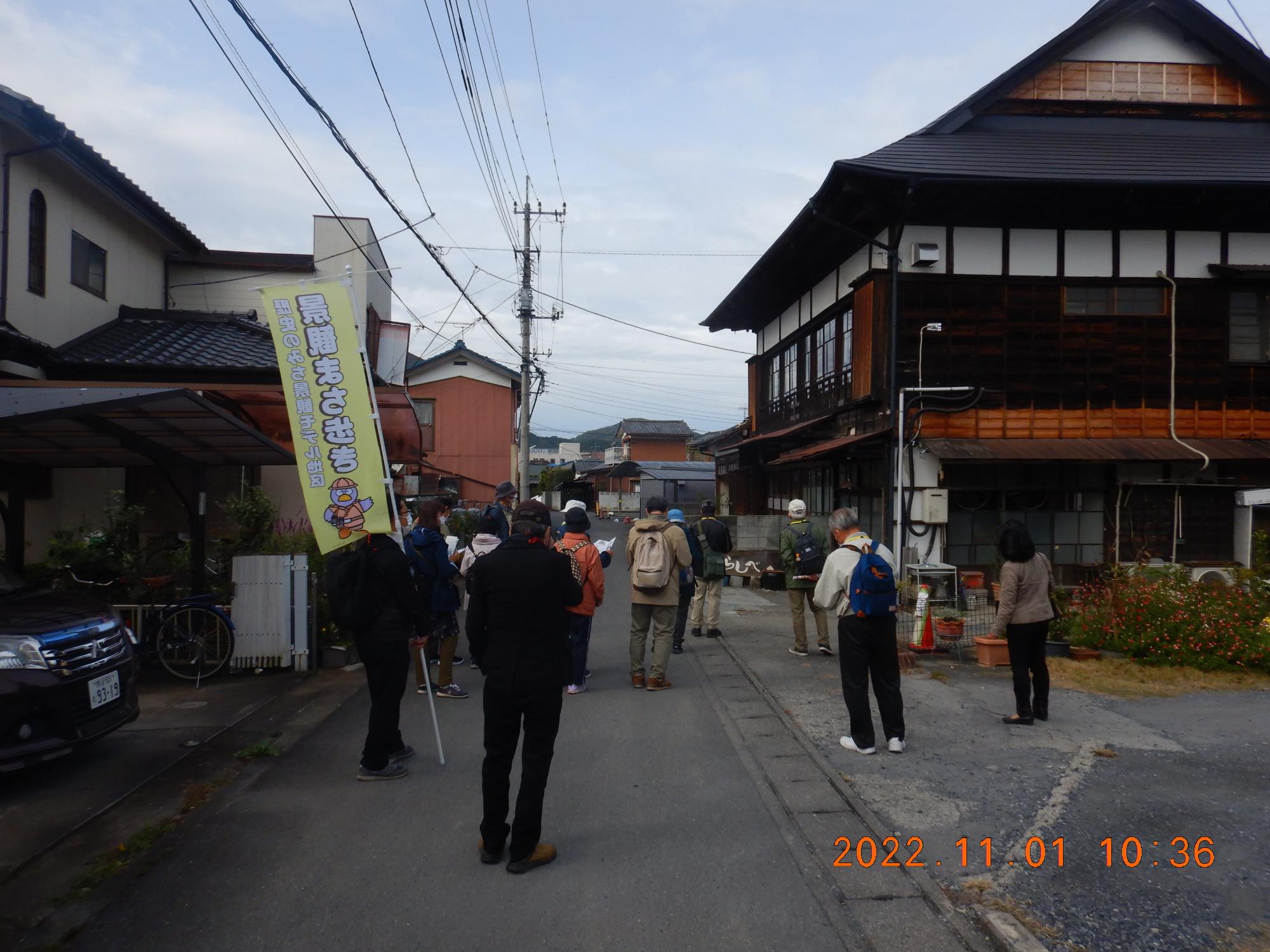 参加者達が住宅街にある趣のある大きな建物を見学している様子の写真
