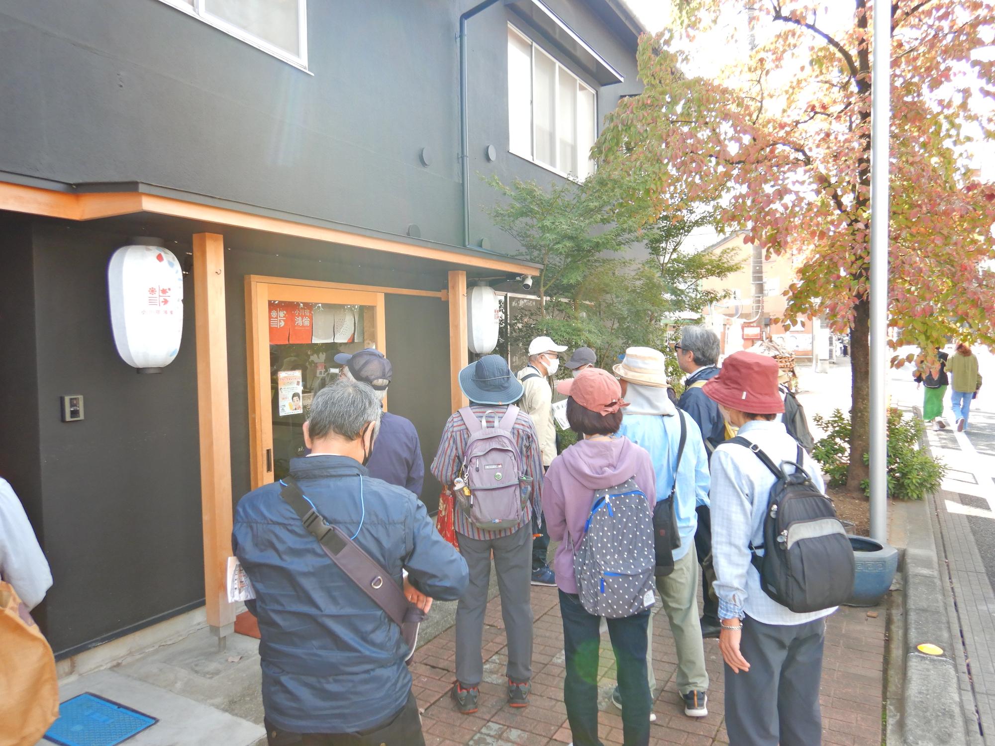 外壁が黒で統一され、柱や入り口部分が木製の店舗前に集まっている参加者達の写真