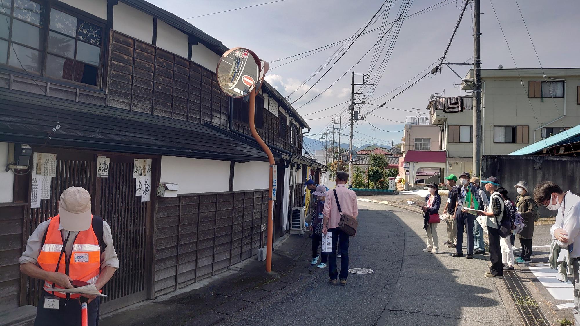 町家造りの家の前で立ち止まり、見学している参加者達の写真