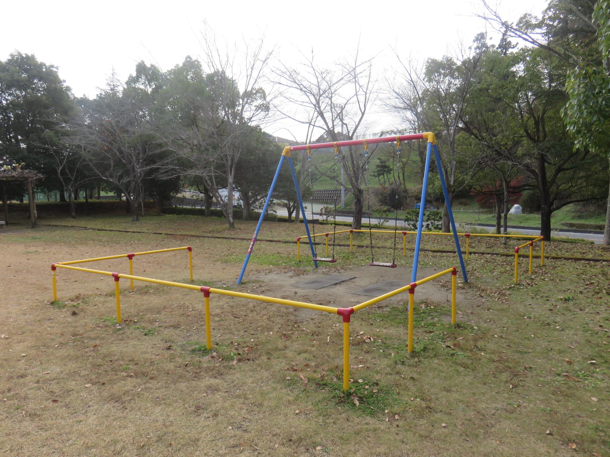 黄色い境界柵の中に設置されているブランコの写真