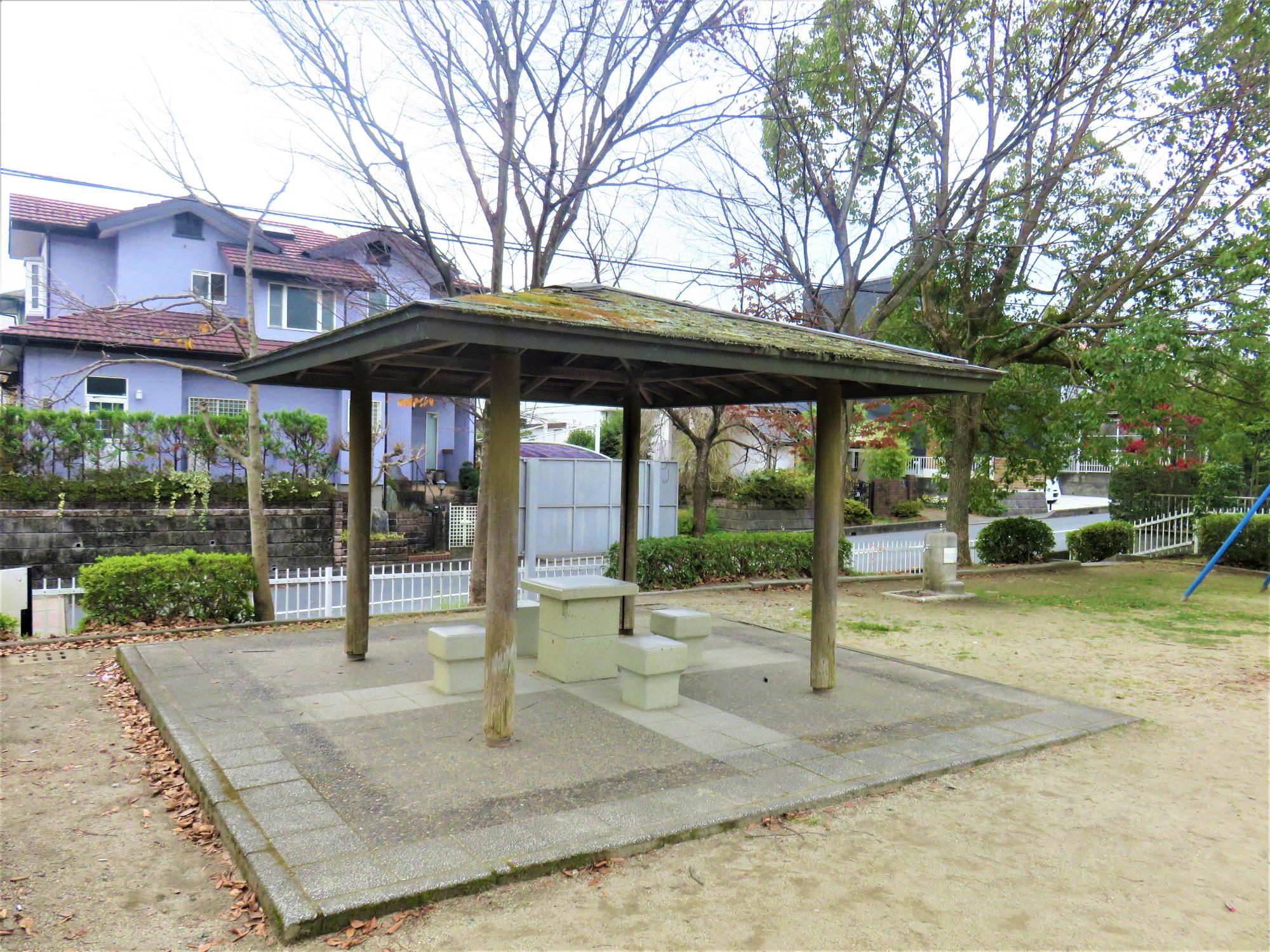 正方形に敷かれたタイルの上にテーブルと椅子が設置されている東屋の写真