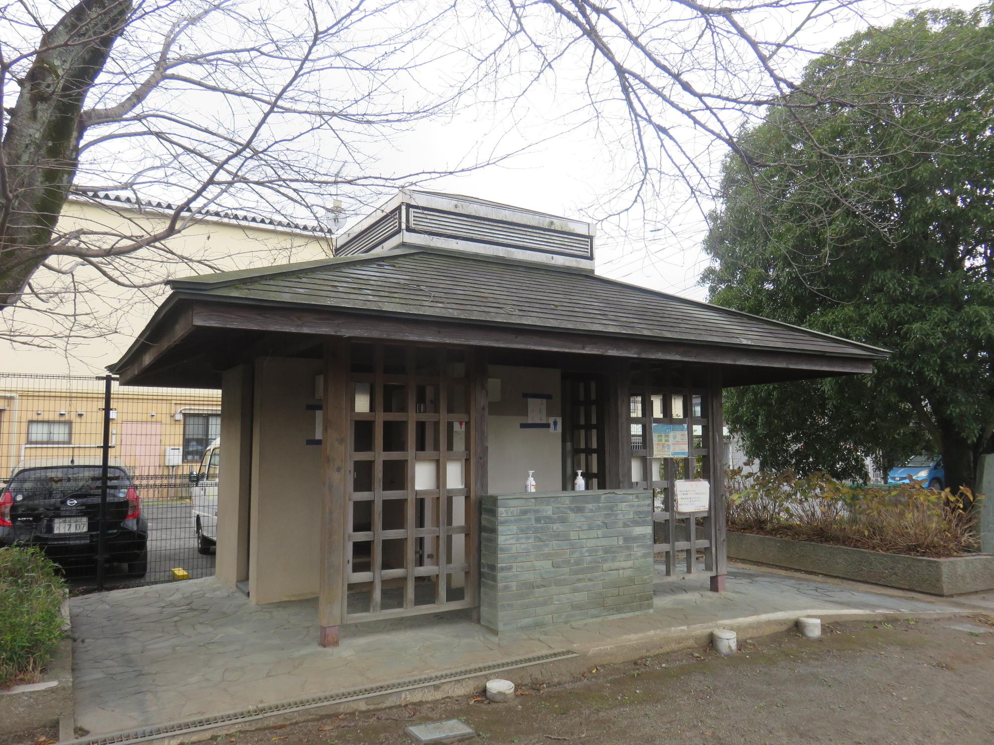 入り口前に格子状の目隠しフェンスが設けられているトイレの建物外観を写した写真