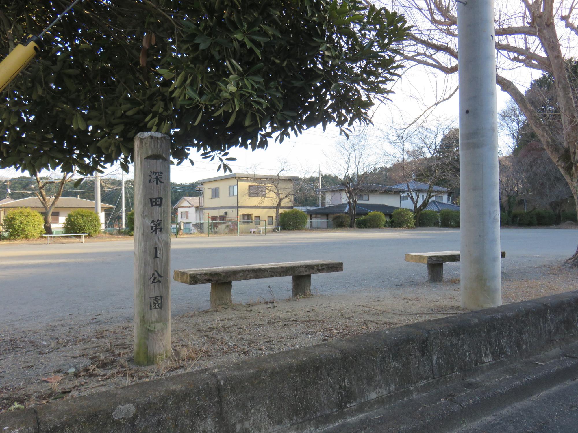 木々や生垣に囲まれた敷地内に2台のベンチが設置された深田第1公園の写真