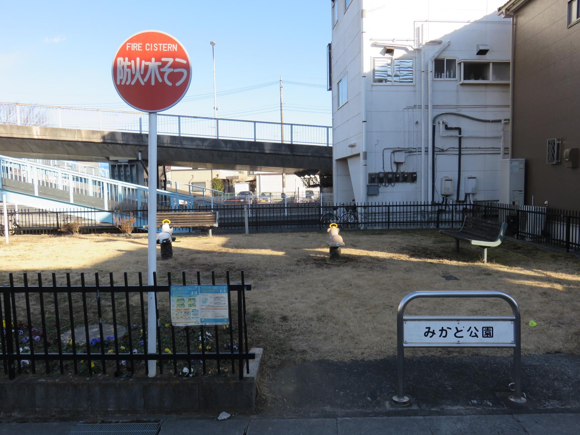 民家に隣接し黒色のフェンスに囲まれた敷地内に2台のスプリング遊具やベンチが設置された御門公園の写真