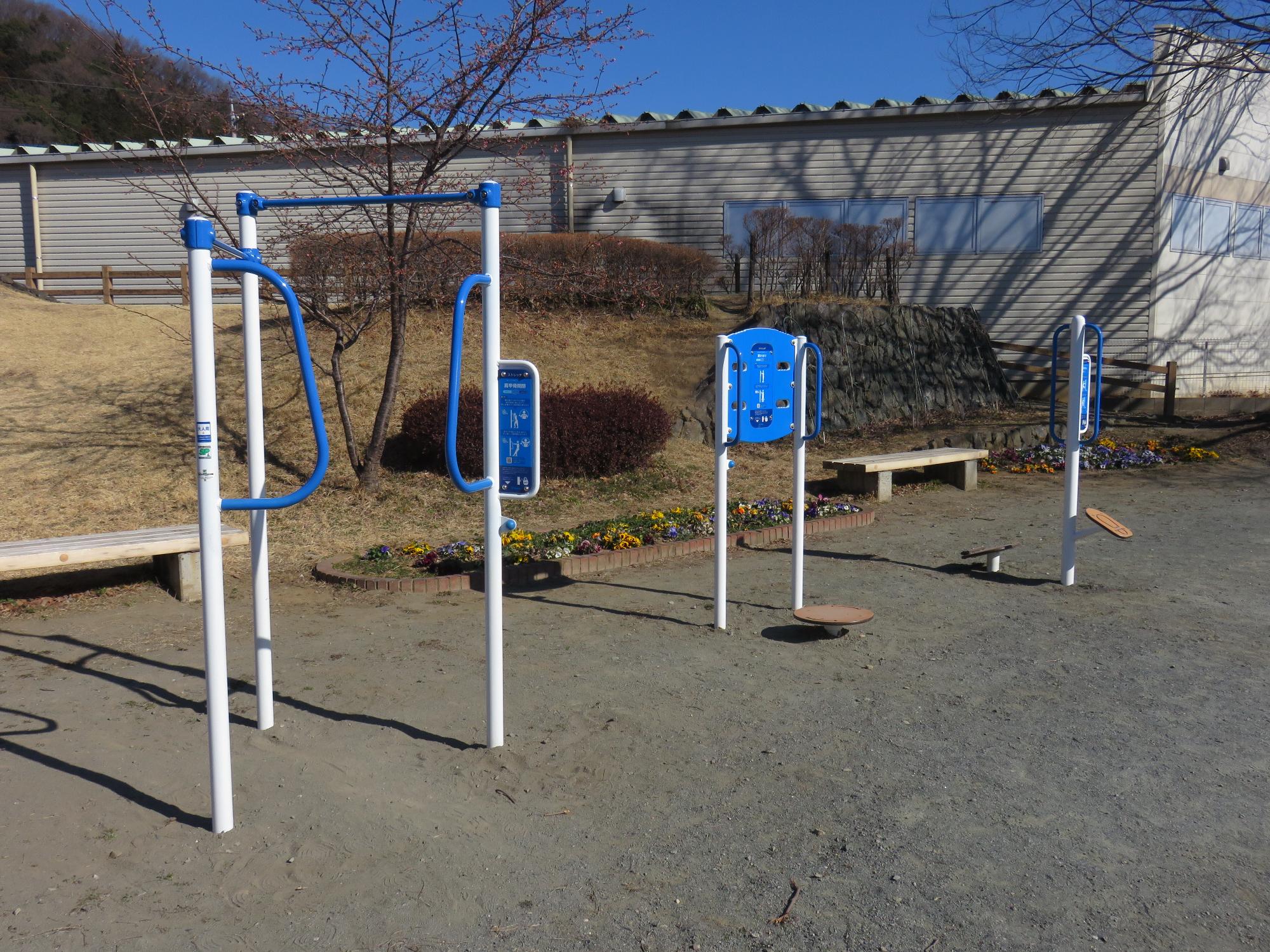 ベンチのそばに設置されている三種類の健康遊具の写真