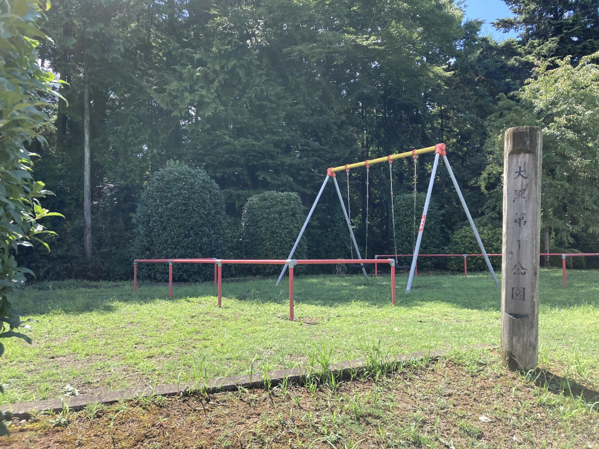 木々が鬱蒼と茂った敷地内にブランコが設置された大黒第1公園の写真