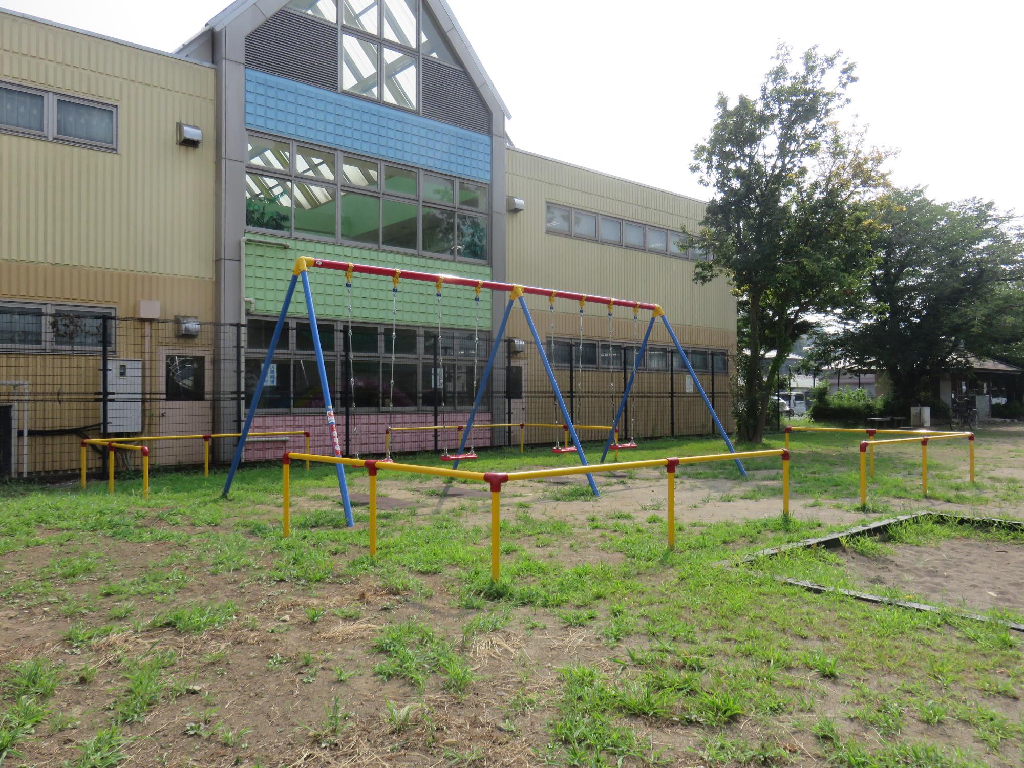 周りを赤い境界柵で囲まれた中に設置されているブランコの写真