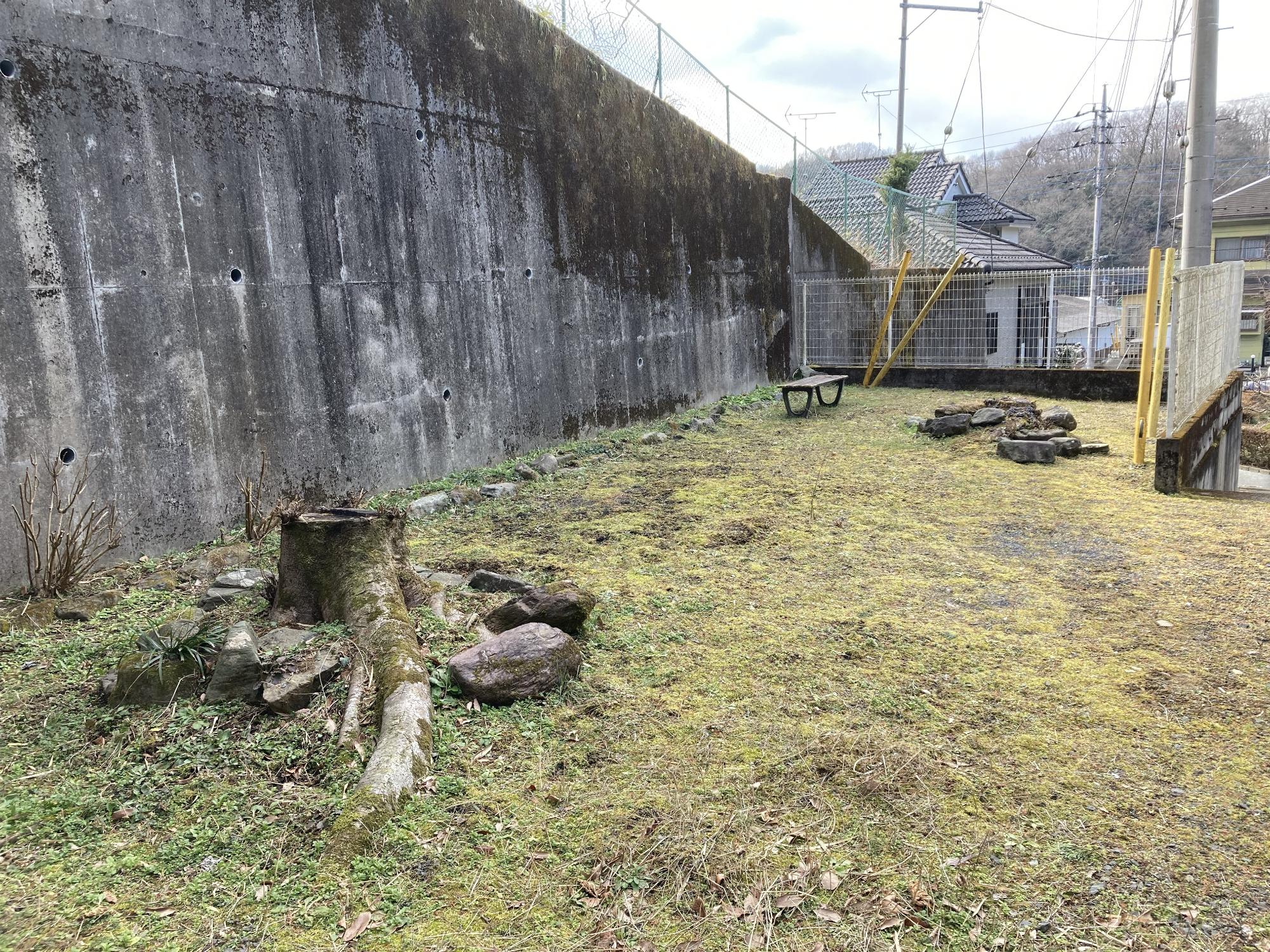 高いブロック塀とフェンスで囲まれた狭い敷地内に1台のベンチが設置された青山第2公園の写真