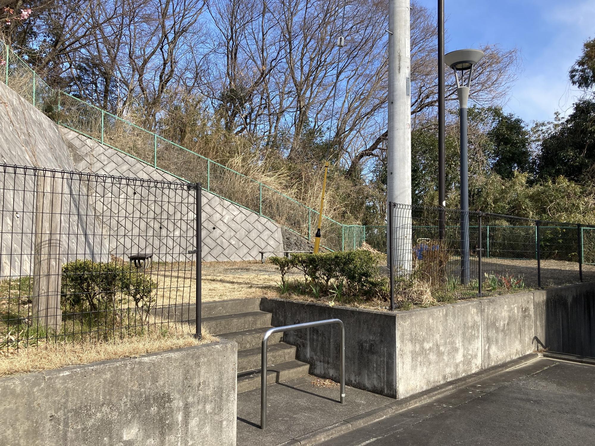 フェンスで囲まれた敷地内に街灯と2台のベンチが設置されている小川東第15公園の写真
