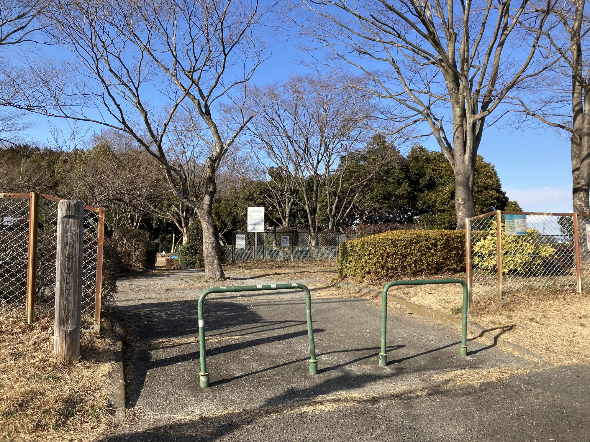 周囲を木々や生垣で囲まれた公園内に、ブランコなどの遊具が設置された小川東第3公園の写真