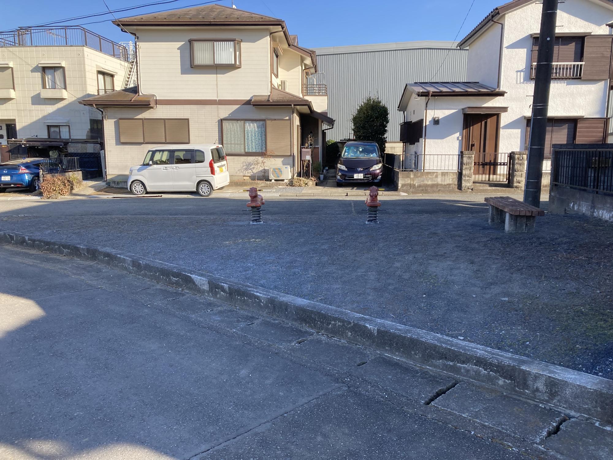 住宅街の角の敷地内に1台のベンチと2台のスプリング遊具が設置された中爪南公園の写真