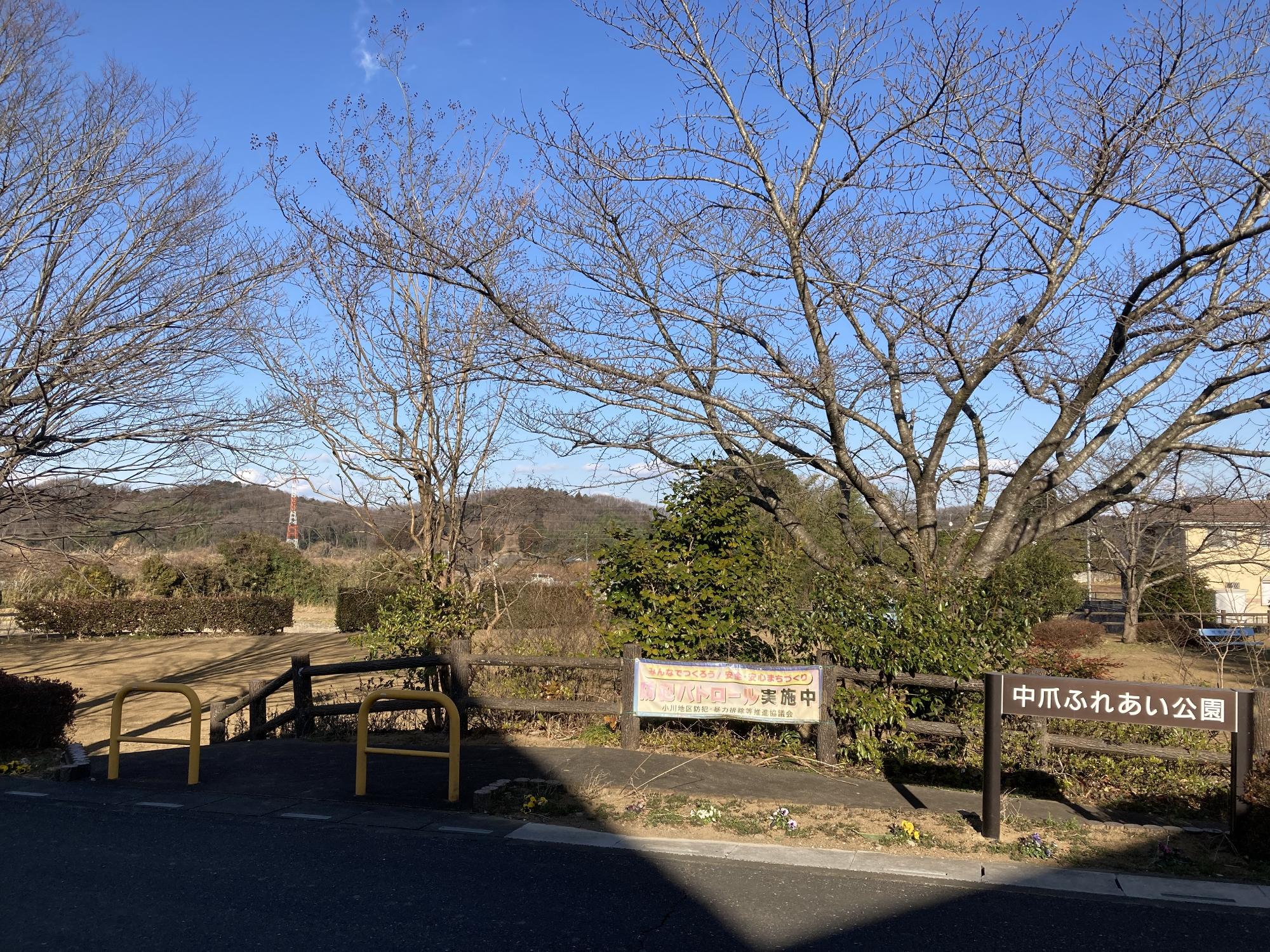 生垣や木々に囲まれた敷地内に水色のベンチが設置された中爪ふれあい公園の写真