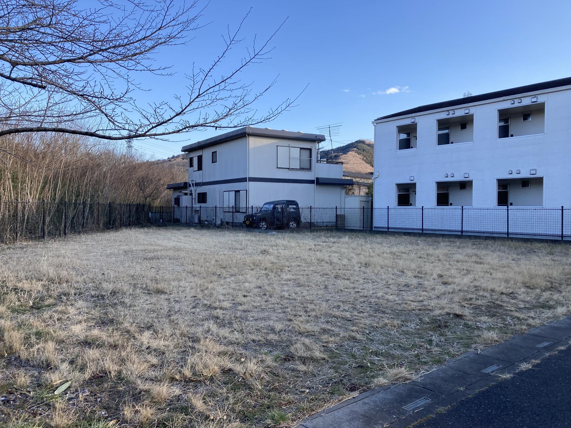 アパートや民家に隣接した黒色のフェンスに囲まれた小川北公園の写真