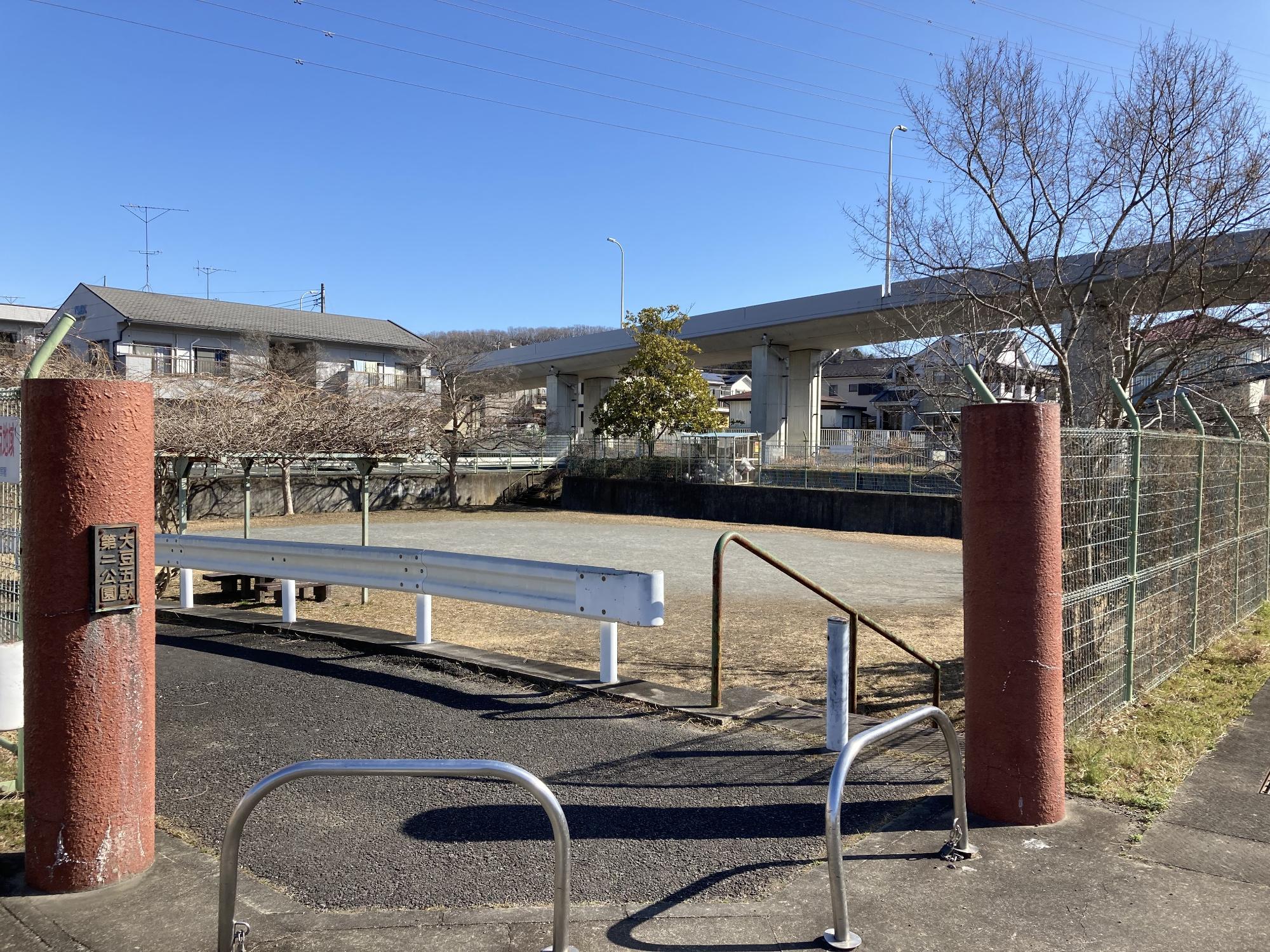 階段を下りた低い位置にある敷地内にパーゴラやベンチが設置された大豆五駄第2公園の写真