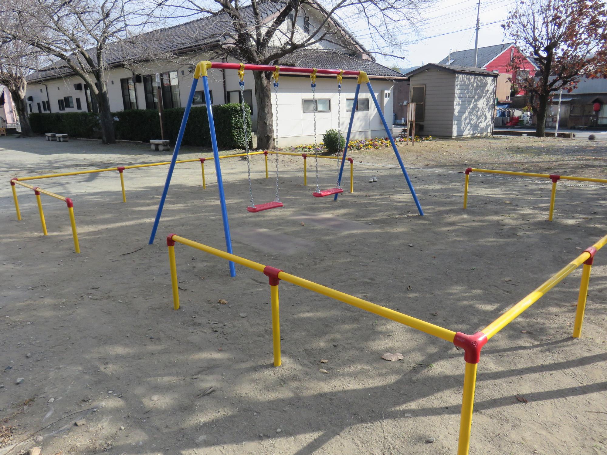 黄色い境界柵に囲まれた中に設置されたブランコの写真