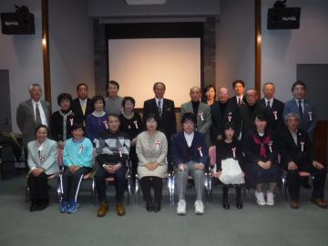 1列目の方々が椅子に座り、三列に並んでいる受賞者の方々と松本町長との記念撮影の写真