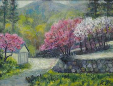 山の手前の山道沿いにある石塀の上や通りにピンク色や白色の花が咲いた木が立っている風景を描いた神田 和子さんの作品