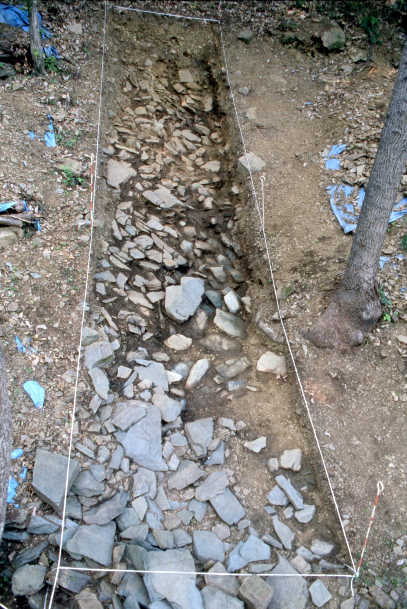 地面の一角を一段低く掘り下げたところに屑石がたくさん検出されておりその箇所をひもで区切っている調査風景の写真