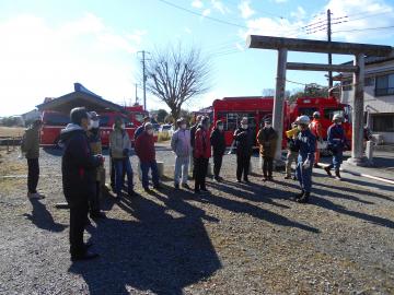 鳥居の前で訓練の参加者に向けて消防職員が拡声器を使い話をしている写真