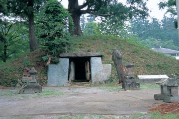 木々が生えた丘にある方墳で近くに祠のようなものが設置されている穴八幡古墳の写真