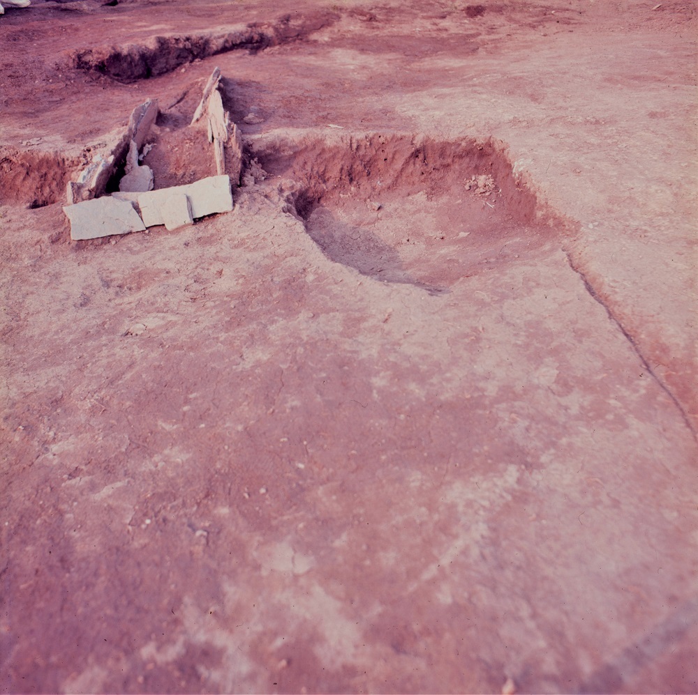 発掘調査で四角形にかたどられた溝の右上側に、穴が掘られている様子の写真