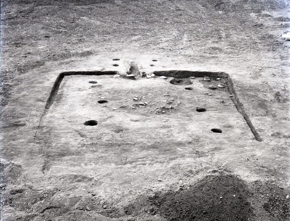 正方形に掘られた溝の中に複数の穴が掘られており、溝の外側にも穴が4つある住居跡の写真
