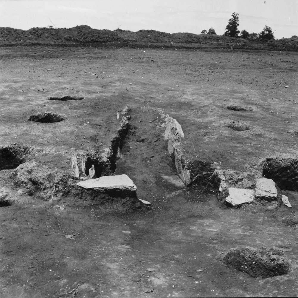 両脇にそれぞれ穴が複数あいており中心に溝が掘られ道のようになっている様子のカマドの写真