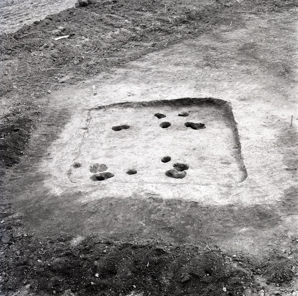 正方形に掘られた溝の中に複数の穴が掘られている住居跡の写真