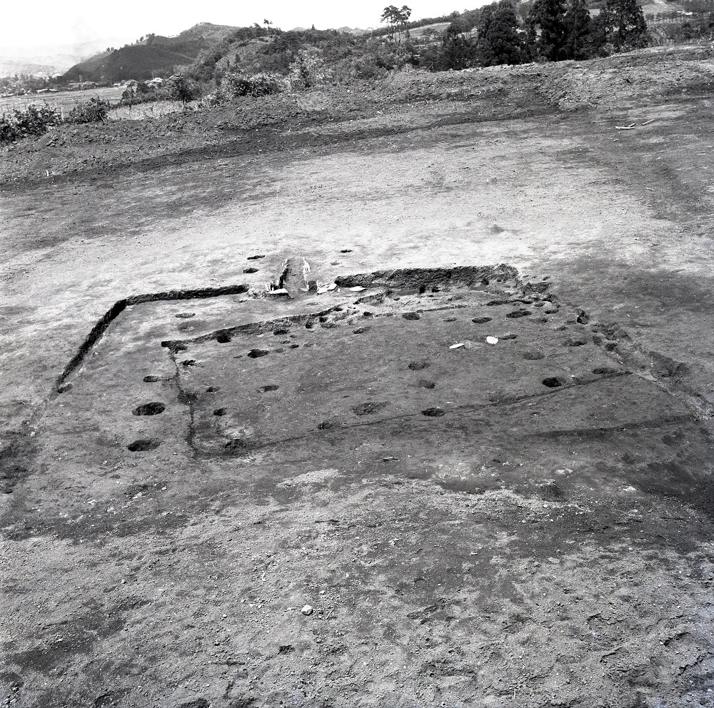 地表面に複数個所のくぼみや穴が開いており周りに四角にかたどられた溝がある住居跡の写真