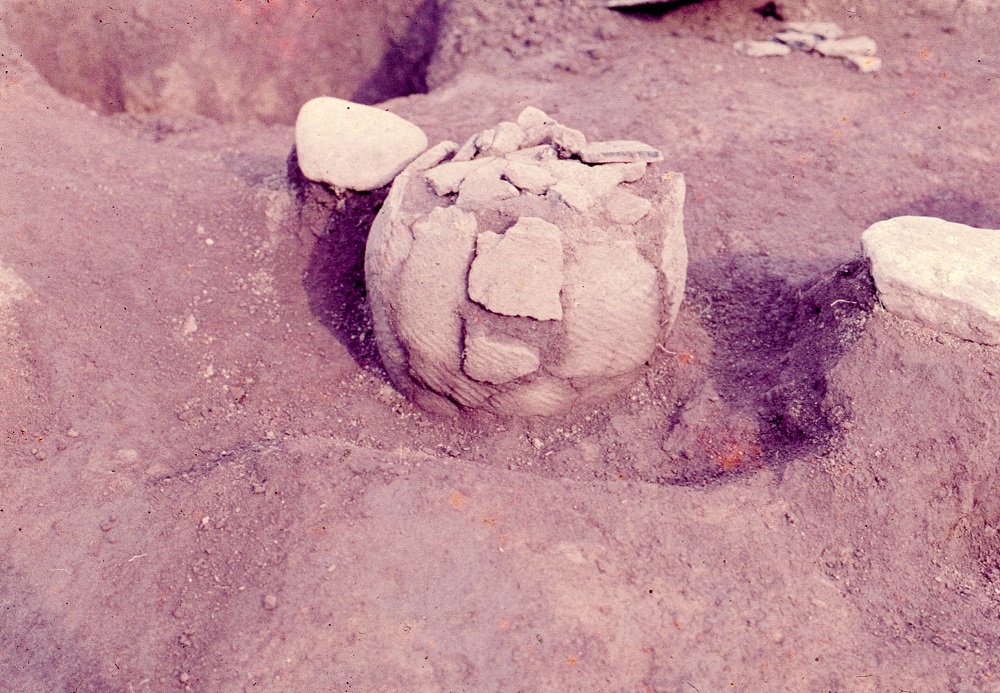 出土されたひび割れているが円形の形をした土器の写真