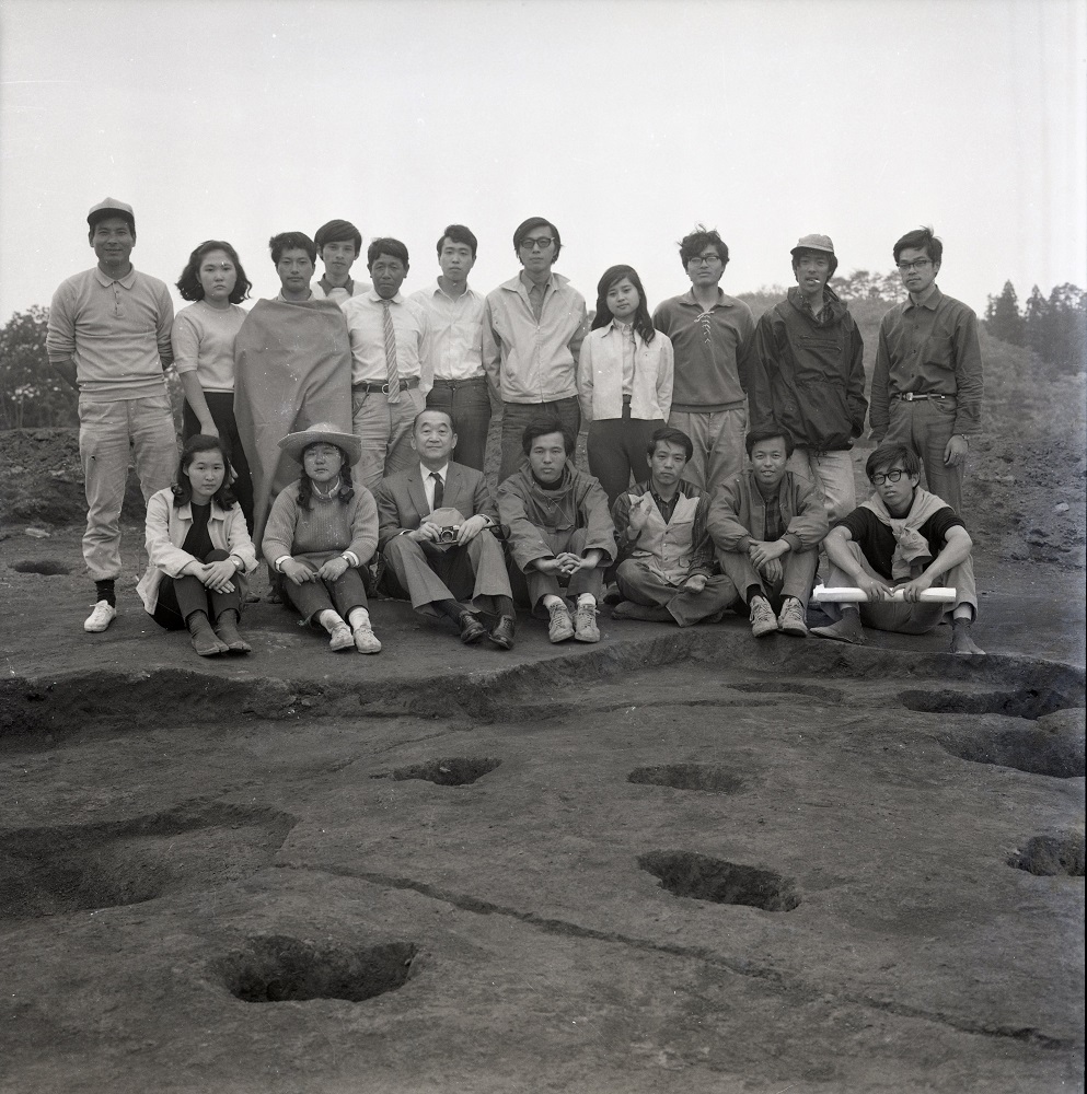 調査参加者が2列に並び前列に7名の男女が座り後列に11名の男女が立っている記念撮影の白黒写真