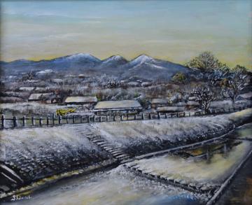 背景には白くなった山々が連なり雪に包まれた町と親水公園が描かれた青木 眞一さんのアクリル画の写真