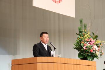 ステージ上に設置された演壇花が添えられた演台の前で町長が式辞を述べている写真