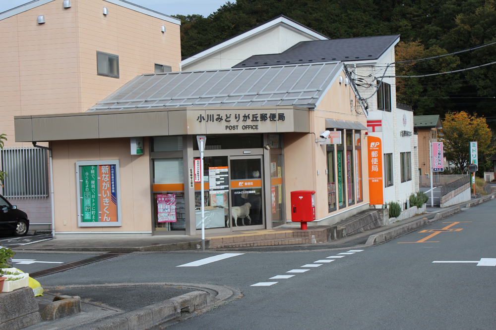 ベージュを基調とした外観の小川みどりが丘郵便局を前方から撮影した写真