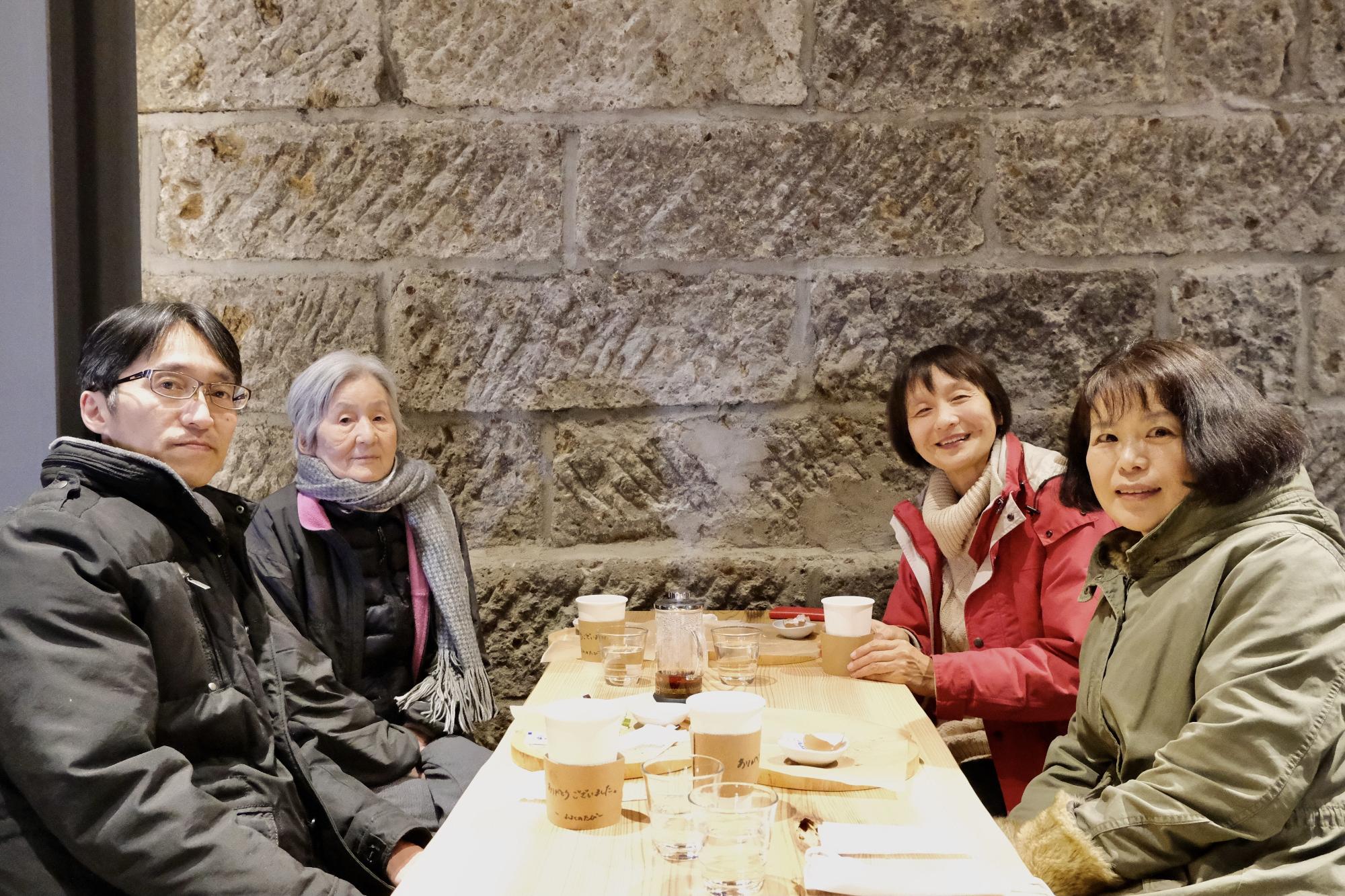 テーブルに座った4名の参加者がカメラに向かって笑顔を見せている和紙行灯作りの様子の写真