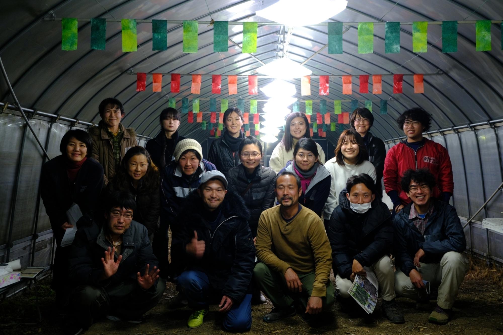 ビニールハウス内で農家さんと参加者が3列に並んでいる写真