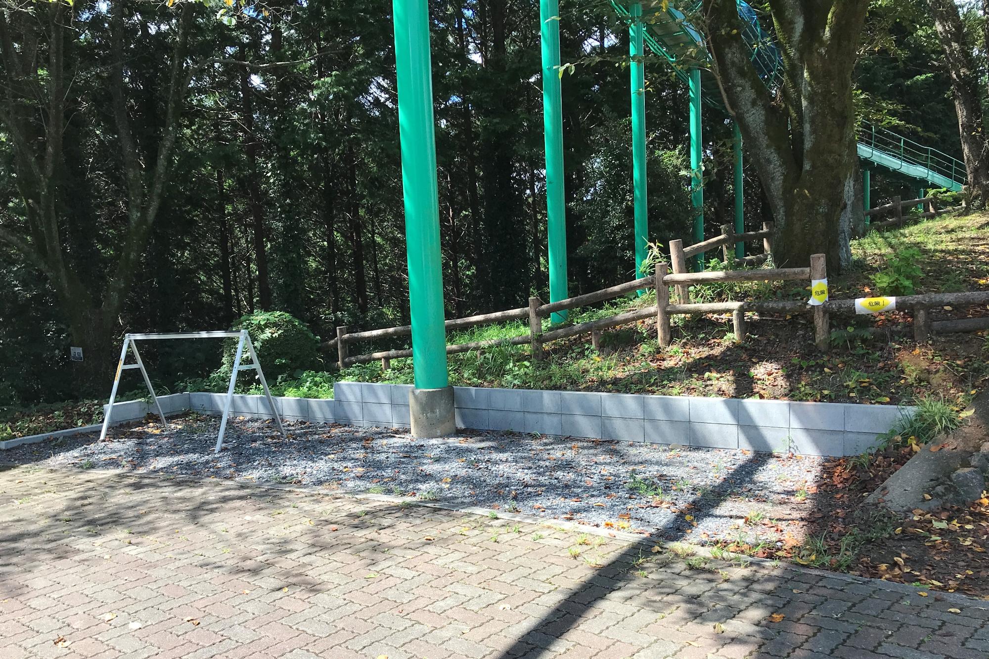木々に囲まれた公園内に1基のサイクルラックが設置された駐輪場の写真