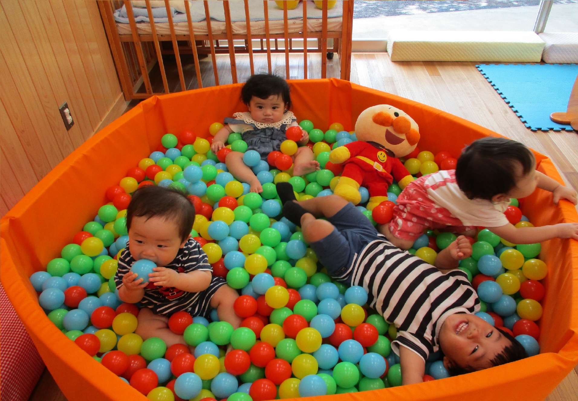 色とりどりのボールが入ったプールの中で座ったり横に寝転んだりしている子供たちの写真