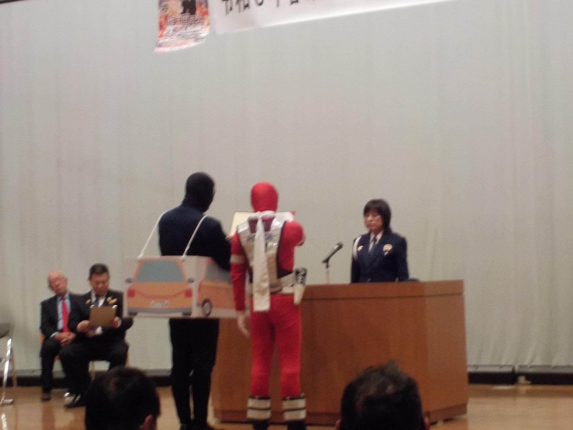 部屋の中で男性たちが全戸点呼の模擬訓練を行っている写真